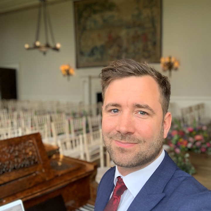Wedding pianist sitting at piano in beautiful stately home wedding venue in the uk