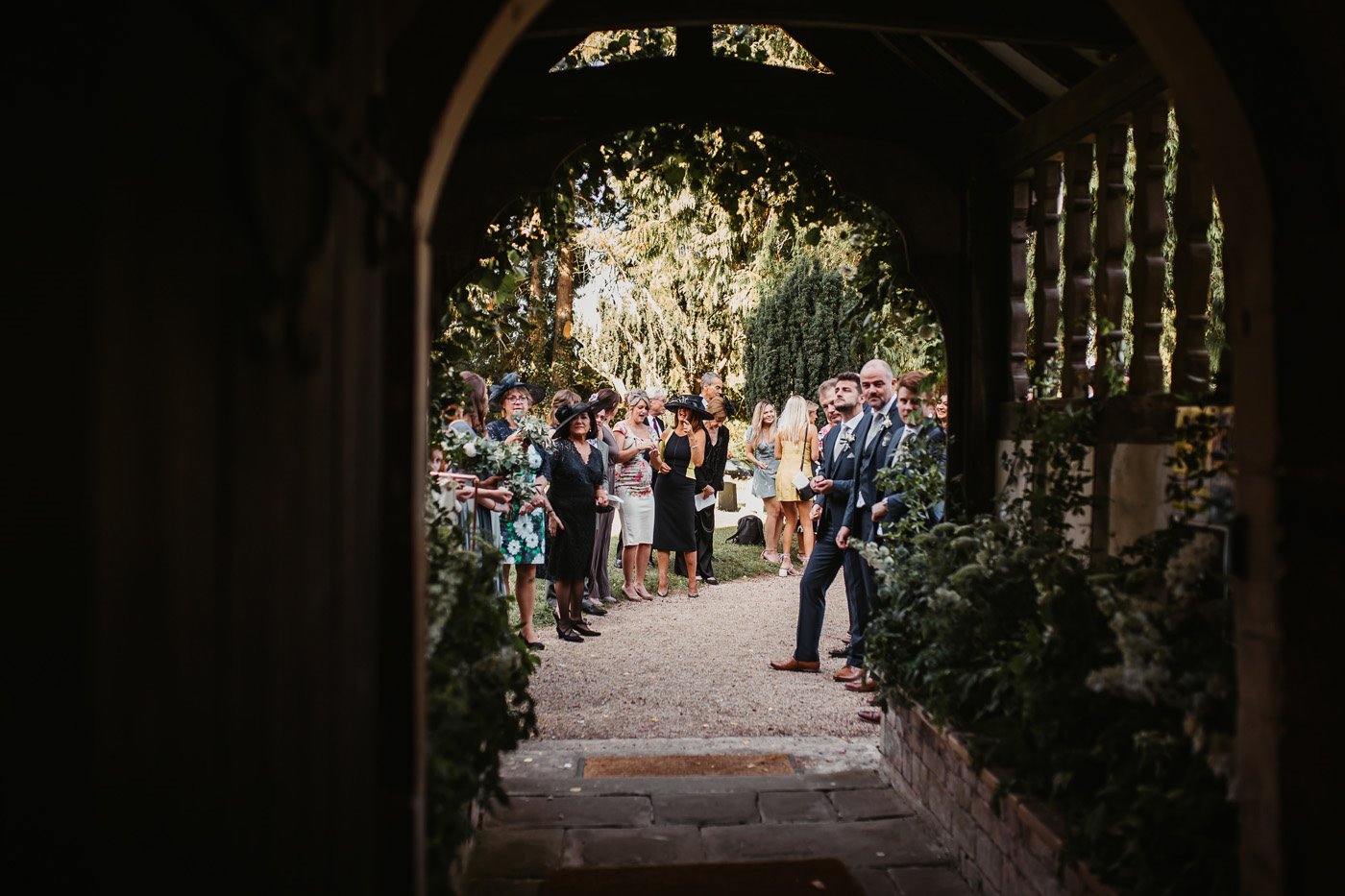 Beautiful church doorway looks out to guests waiting to throw confetti at a wedding in the uk