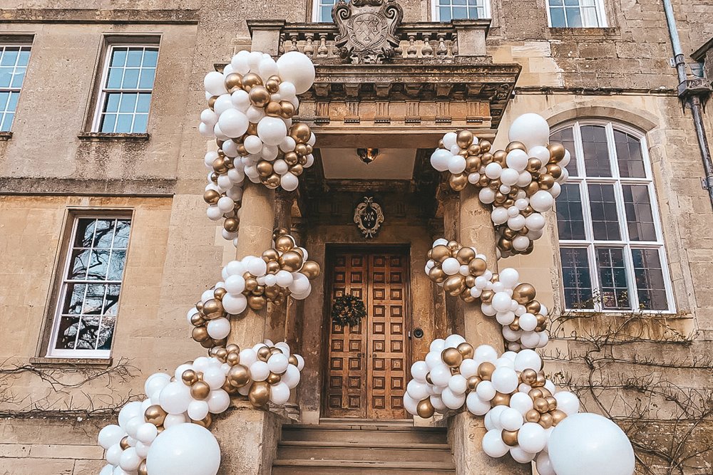 Wedding balloon installation in gold and white on the steps of a stately home for a wedding fair in Gloucestershire