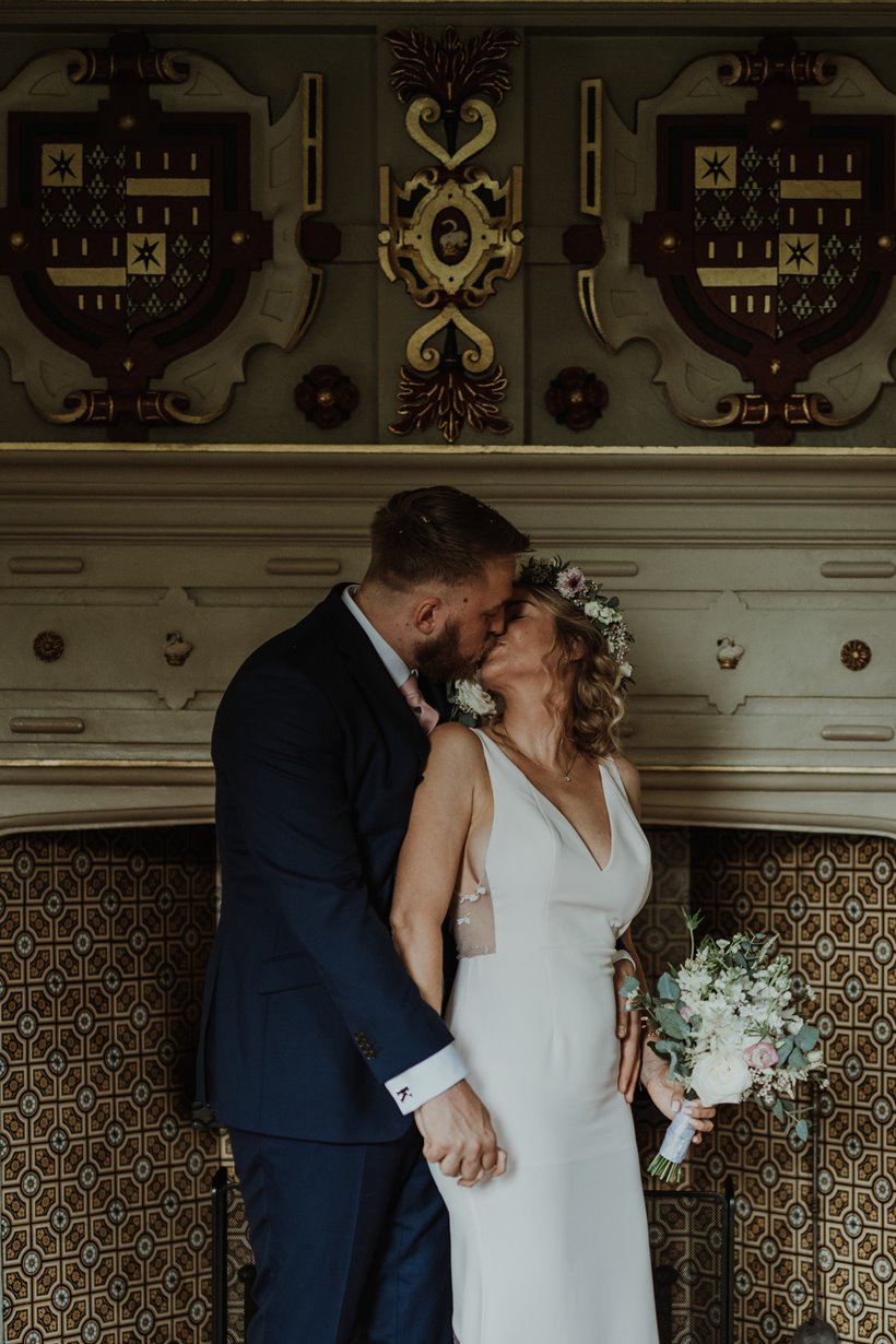 Bride and groom kiss in drawing room at elmore court