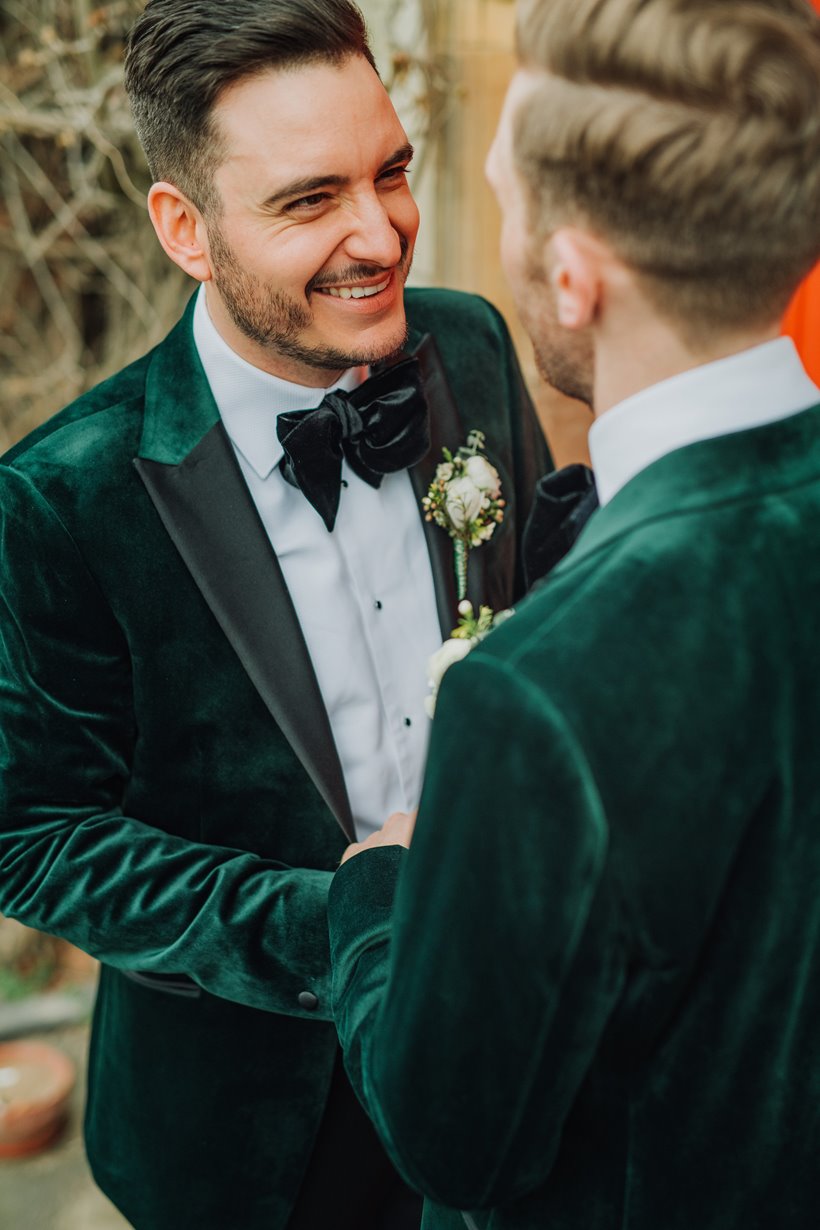 Gay couple happily married in green velvet suits with bow ties