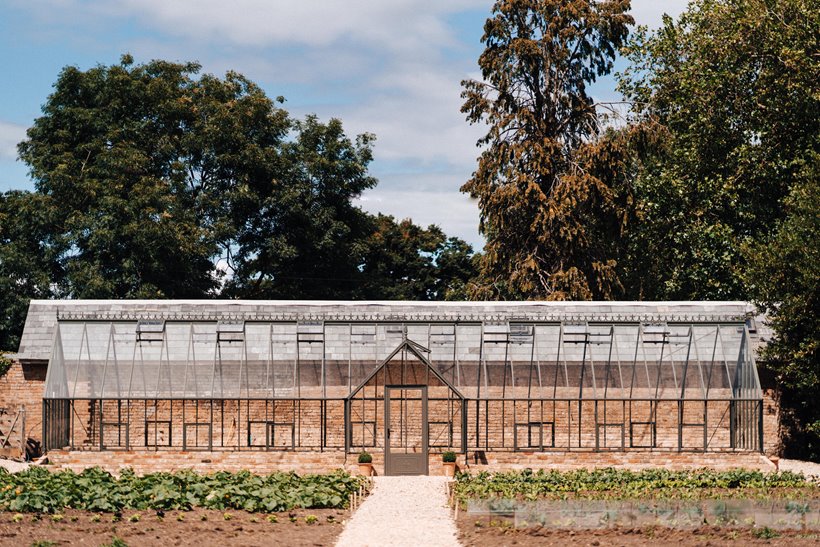 Glass house at elmore court with organic seedlings growing in neat beds around it in the walled garden for future outdoor weddings and greenhouse garden receptions