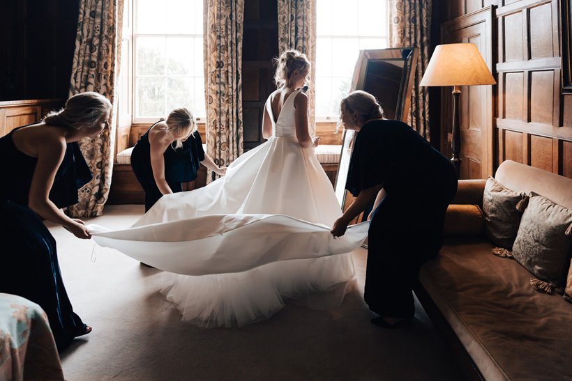 Getting ready on wedding day bridal party spread out brides beautiful full skirt and train on wedding dress at elmore court