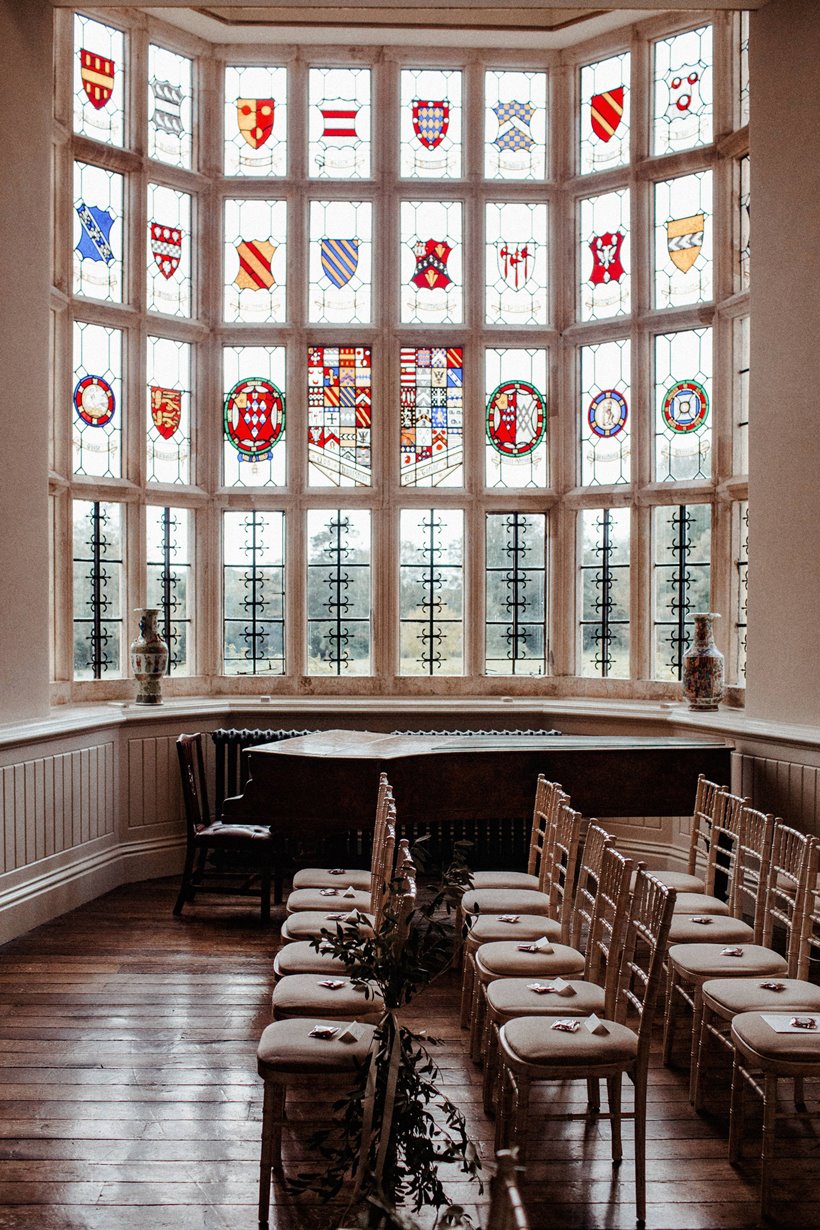 Chairs for wedding ceremony in front of Stained glass windows for a romantic autumn wedding at elmore court