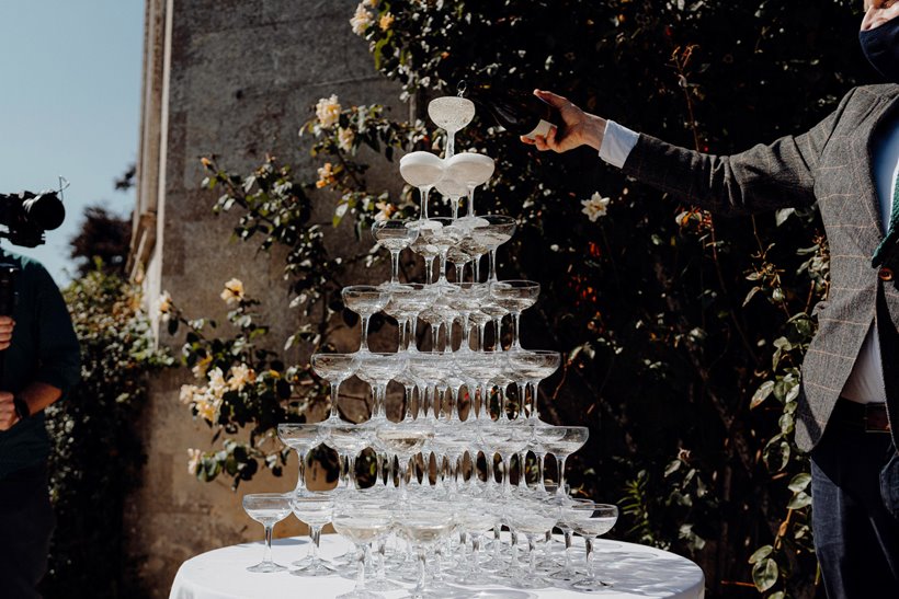 A groom pouring champagne into an impressive champagne tower at Elmore Court