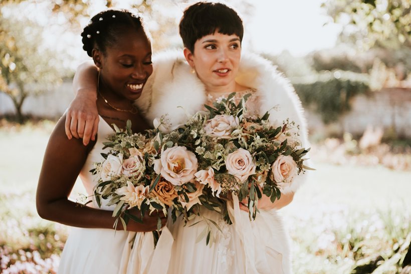 Two brides wearing pearls holding beautiful blush bouquets on their wedding day outside stately home elmore court