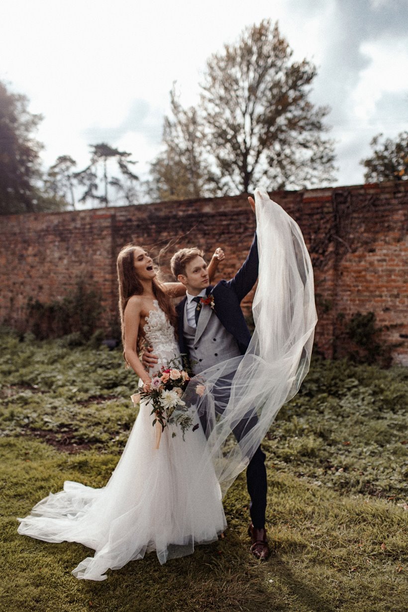 Cool bride and groom pose for laid back photos in the autumn gardens of their wedding venue