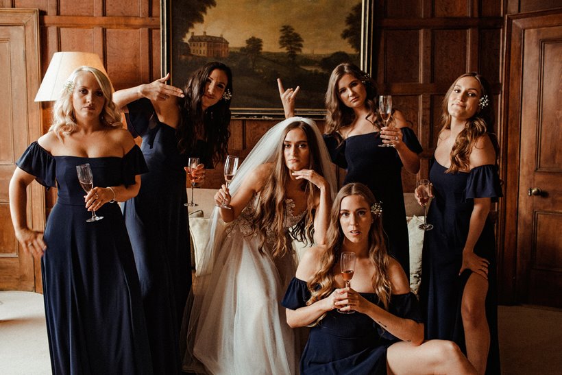 Bridal party pose in warm wood panelled bedroom in mansion house in the autumn 