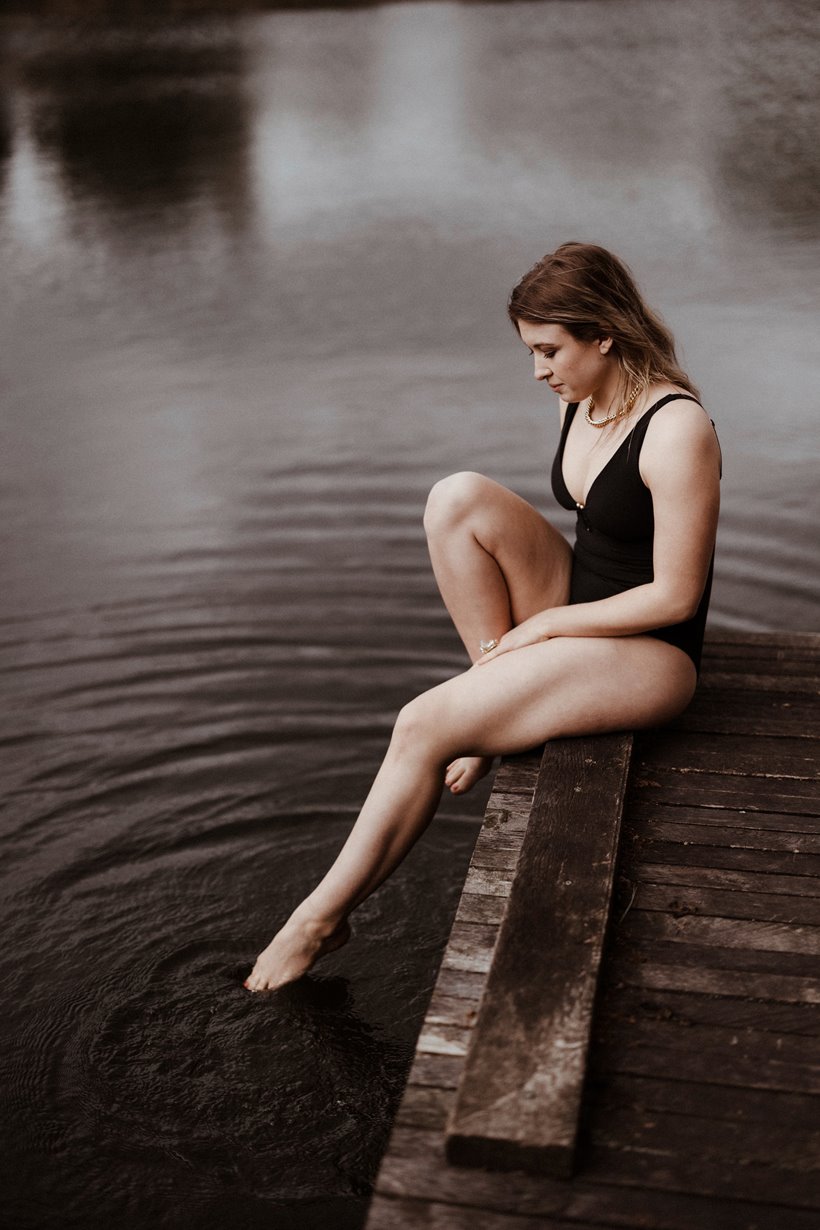 wild bride swims in open water on wedding day dipping her toe in the lake testing water before diving in